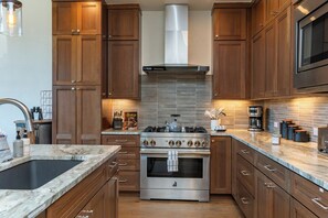 Une cuisine moderne avec des meubles en bois, une cuisinière en acier inoxydable et un dosseret carrelé.