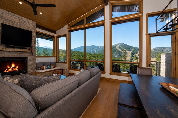 Ein modernes Wohnzimmer mit Kamin, großen Fenstern und Bergblick.