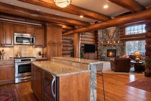L’intérieur d’une cabane en rondins comprend une cuisine, une cheminée en pierre et un coin salon confortable.