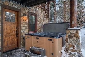 Une façade en pierre, une porte en bois et un jacuzzi.