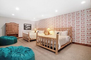 A bedroom with two single beds, a wooden wardrobe, a green bean bag chair, and a patterned wallpaper.