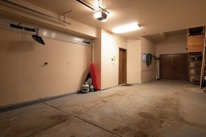 A spacious garage with a concrete floor, a ceiling-mounted projector, and a wooden door. - Hygge Hideaway | Private Hot Tub (Winter Park)