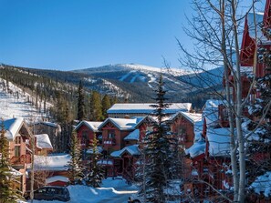 A snow-covered mountain village with wooden cabins and a ski slope in the background. - Hygge Hideaway | Private Hot Tub (Winter Park)