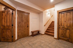 Un couloir avec des portes en bois, un banc et un escalier.