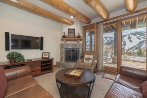 Ein Wohnzimmer mit Kamin, Ledersofas, einem Couchtisch und einem Fernseher.