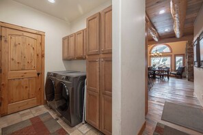 A laundry room with wooden cabinets and a washing machine. - Lakota Majesty | Pet Friendly | Hot Tub | Sauna | Across From Resort (Winter Park)