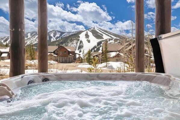 Ein Whirlpool mit Blick auf ein Gebirge und ein Gebäude im Hintergrund.