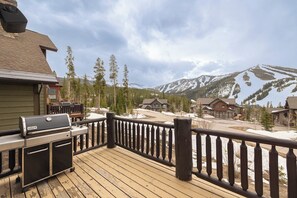 A wooden deck with a grill, overlooking a residential area with houses and mountains. - Lakota Majesty | Pet Friendly | Hot Tub | Sauna | Across From Resort (Winter Park)