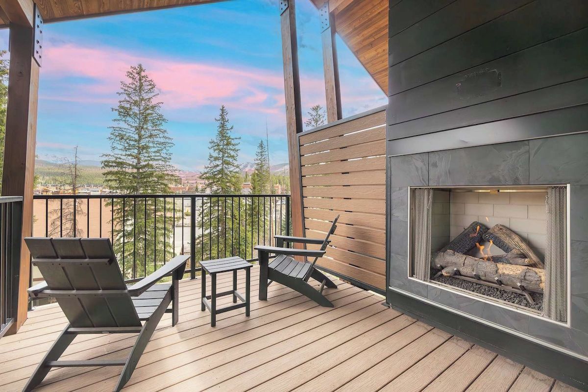 Une terrasse avec un foyer, deux chaises et une table.