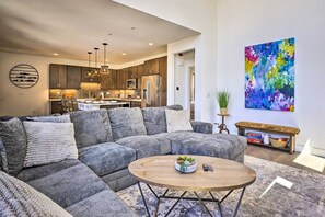 A modern living room with a sectional sofa, a round coffee table, and a kitchen in the background. - Rendezvous Retreat | Pet Friendly with Peak Vistas | Walk to Trails (Fraser)