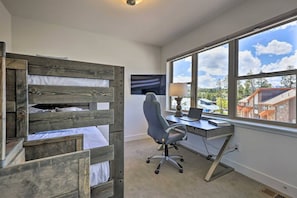 A room with a bunk bed, a desk with a chair, a television, and a large window with a view of buildings. - Rendezvous Retreat | Pet Friendly with Peak Vistas | Walk to Trails (Fraser)