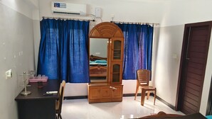 Quarto de hotel com cama, escrivaninha, guarda-roupa e uma cadeira.