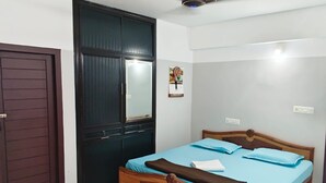 Quarto com cama de madeira, porta escura e ventoinha no teto.