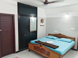 Ein Schlafzimmer mit einem hölzernen Bett, einer dunklen Tür und einem Deckenventilator.