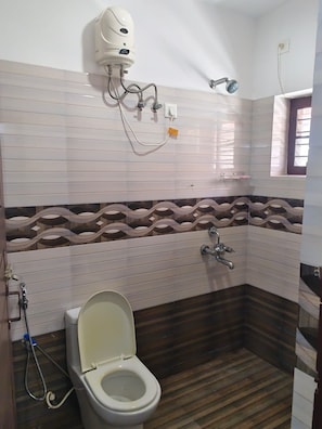 A bathroom with a toilet, shower, and a wall-mounted heater.