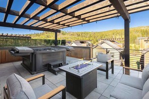 An outdoor patio with a hot tub, grill, and seating area. - Gather & Glow | Downtowan House | Private Hot Tub (Winter Park)