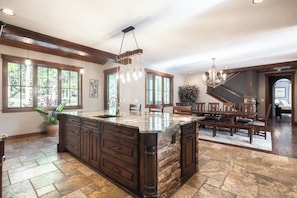 Una cocina amplia con una isla grande, armarios de madera y un comedor con una escalera.