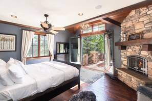 Ein Schlafzimmer mit einem Bett, einem Kamin aus Stein und Blick ins Freie.