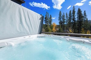 Ein Whirlpool mit freiem Blick auf eine bewaldete Landschaft und ein Gebäude im Hintergrund.