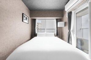 A hotel room with a large bed, a window with curtains, a bedside lamp, and a view of the outside. - Edgewater Terrace 211 (Sapporo)