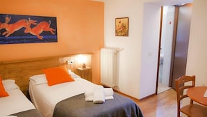 A hotel room with two beds, a wooden headboard, a radiator, a painting, and a door leading to another room. - Indren Hus - Residence (Alagna Valsesia)
