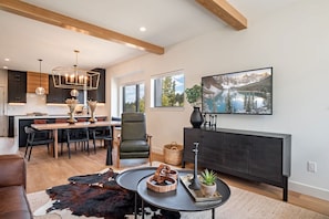 A modern living space with a dining area, a sofa, a coffee table, and a painting on the wall. - Lumen Haus | Pet Friendly | Modern Mountain Home (Fraser)
