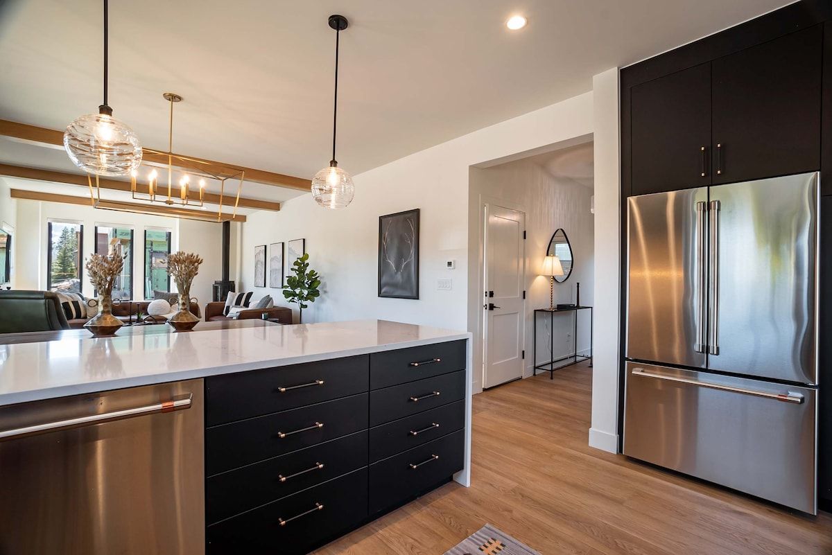 A modern kitchen with a large island, stainless steel appliances, and pendant lighting.