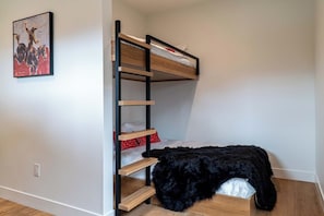 A bunk bed with a ladder, a black furry rug, and a poster on the wall. - Lumen Haus | Pet Friendly | Modern Mountain Home (Fraser)