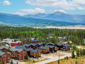 A residential area with multiple wooden cabins, a road, and a forested landscape with mountains in the background. - Lumen Haus | Pet Friendly | Modern Mountain Home (Fraser)