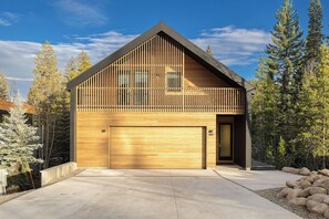 A modern two-story house with a wooden facade, a garage, and a balcony. - Creekside Retreat | Private Hot Tub | Secluded Modern Retreat (Winter Park)