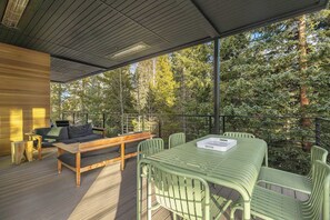 An outdoor deck with a wooden bench, a table, and chairs. - Creekside Retreat | Private Hot Tub | Secluded Modern Retreat (Winter Park)