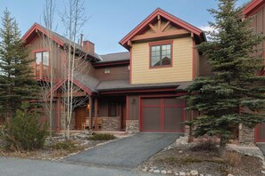 Un bâtiment à deux étages, avec des fondations en pierre, un toit rouge et un porche à l’avant.