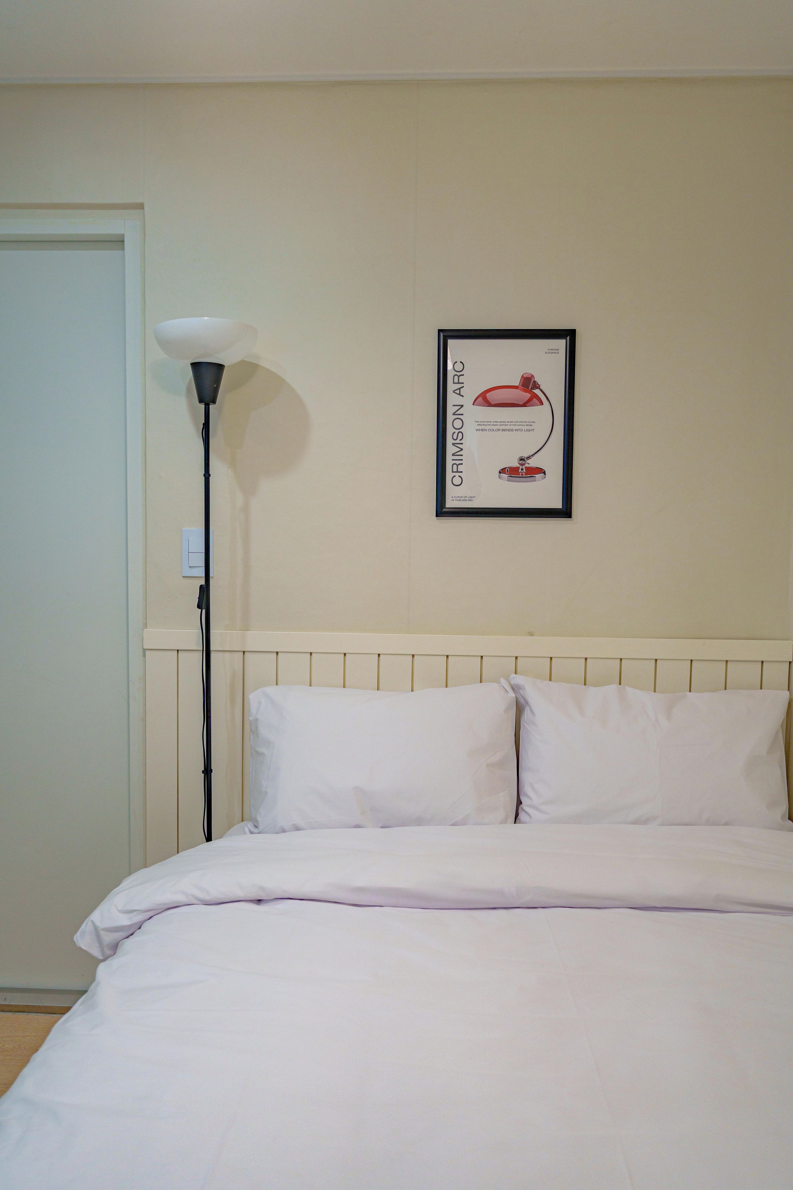Un dormitorio con una cama, una lámpara y un cuadro en la pared.