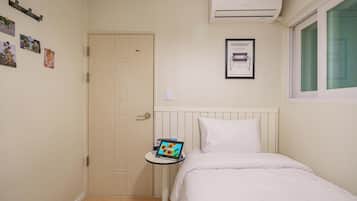 Een slaapkamer met een bed, een nachtkastje met een tablet, een deur en een airconditioning.