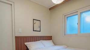 A bedroom with a bed, a window, a wall clock, and a hanging light fixture. - WAYHOME (Seoul)