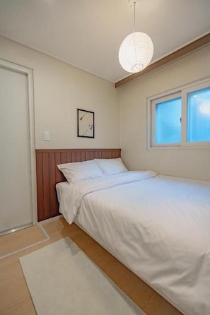 Una camera da letto con un letto, una finestra, una sveglia a parete e un lampadario.