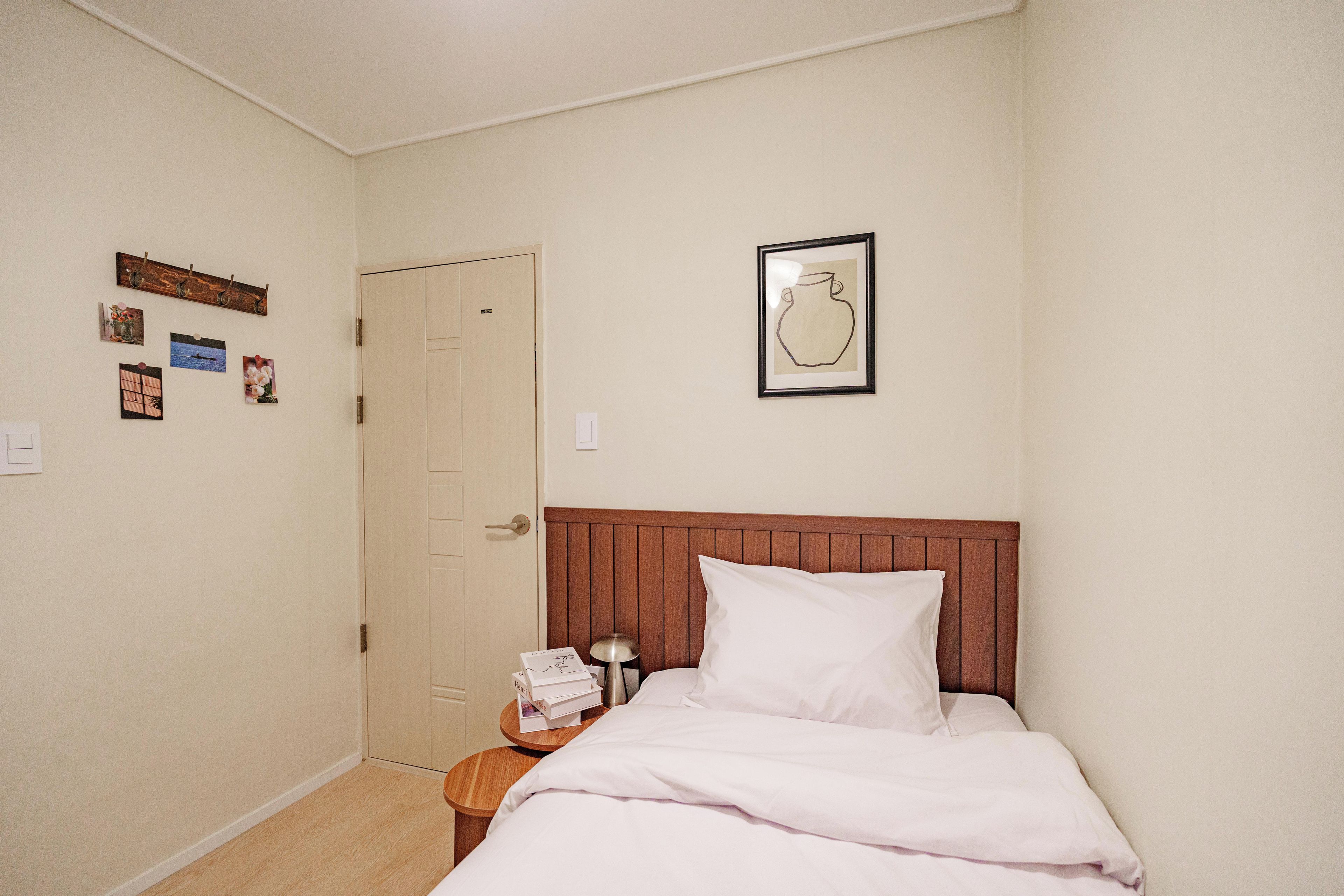 Een slaapkamer met een bed, nachtkastje, deur en decoraties aan de muur.