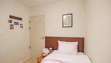 Een slaapkamer met een bed, nachtkastje, deur en decoraties aan de muur.