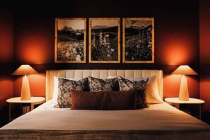 A hotel room with a bed, two bedside lamps, a headboard, and three framed pictures on the wall. - Lakota Lookout | Private Hot Tub | Slope Views (Winter Park)