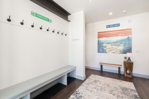 Ein Empfangsbereich mit einer Bank, einem Wandhaken für Kleidung, einer Bank mit Teppich und einem gerahmten Bild an der Wand.