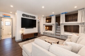 Ein modernes Wohnzimmer mit Flachbildfernseher, einer Couch, einem Couchtisch und einer Treppe mit einem Etagenbett.