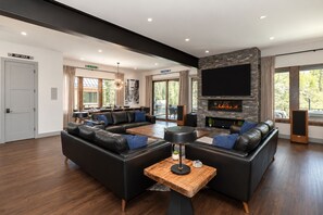 Ein modernes Wohnzimmer mit Kamin, Ledersofas und einem Flachbildfernseher.