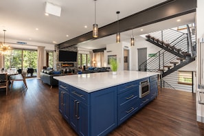 A modern kitchen with a large island, dark blue cabinetry, and a central island with a white countertop. - Dilly Dally Chalet | Private Hot Tub | Colorful & Modern Downtown Home (Winter Park)