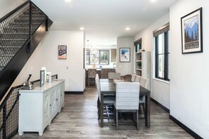 A modern interior with a staircase, dining area, kitchen, and a framed poster on the wall. - Solstice Abode | Pet Friendly | Private Hot Tub | Prime Location (Winter Park)