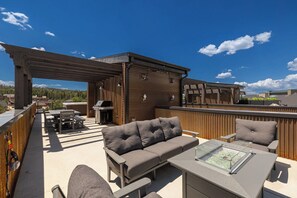 An outdoor patio with a sofa, chairs, and a table, a barbecue grill, and a pergola structure. - Peaks and Pines Villa | Downtown | Private Hot Tub (Winter Park)