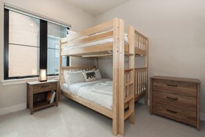 A bunk bed with a nightstand and a dresser in a room with a window. - Peaks and Pines Villa | Downtown | Private Hot Tub (Winter Park)
