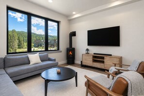 A modern living room with a sofa, coffee table, and TV. - Peaks and Pines Villa | Downtown | Private Hot Tub (Winter Park)