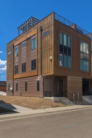 A modern building with a wooden facade, large windows, and a covered outdoor area. - Peaks and Pines Villa | Downtown | Private Hot Tub (Winter Park)