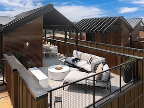 Eine Dachterrasse mit Feuerstelle, Sitzgelegenheiten im Freien und Blick auf die Umgebung.