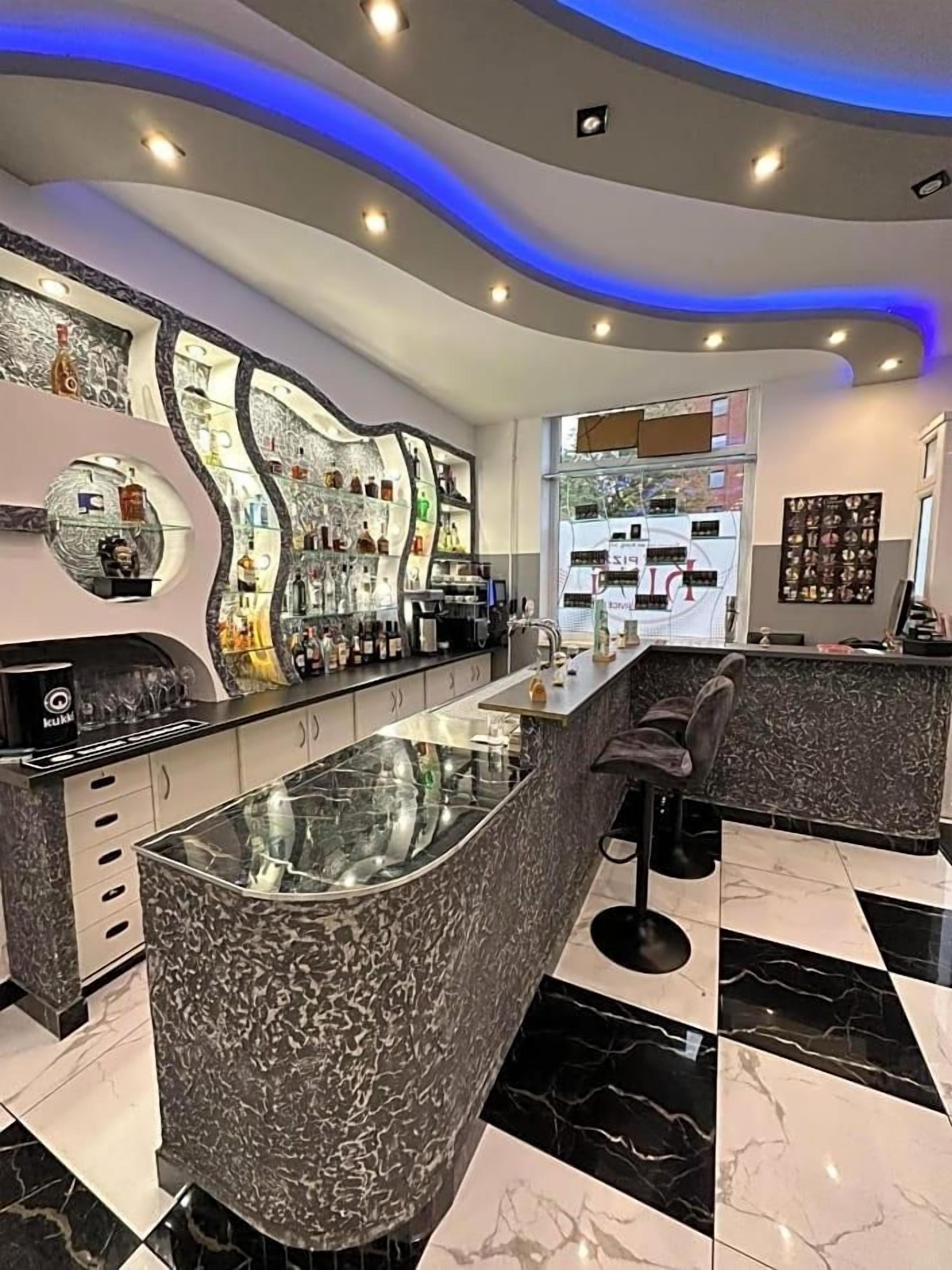 Eine moderne Bar mit einer gebogenen Theke, Barhocker und einer Glasfassade.